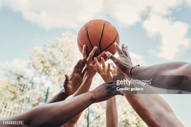 arme von multi-ethik-sportlern werden gegen den himmel erhoben - basketball stock-fotos und bilder