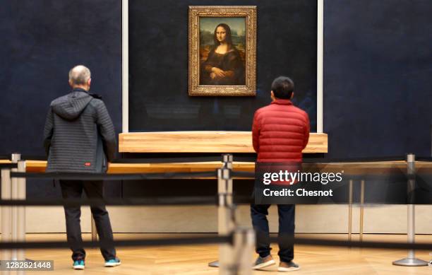 Visitors wearing protective face masks look at the painting of "Mona Lisa" also known as by Italian artist Leonardo Da Vinci inside the deserted...