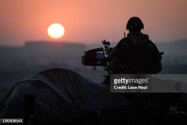 Soldier from the Royal Anglian Regiment guards the perimeter of the camp from a Coyote tactical support vehicle at sunrise during a Mission Rehearsal...