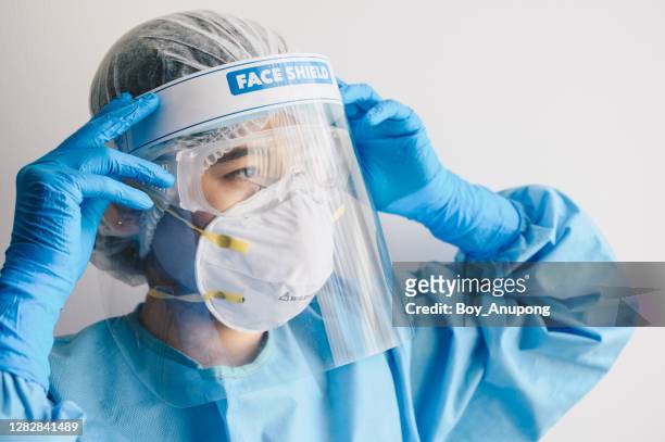 nurse wearing ppe suit and face shield before working in hospital. - protective workwear stock pictures, royalty-free photos & images