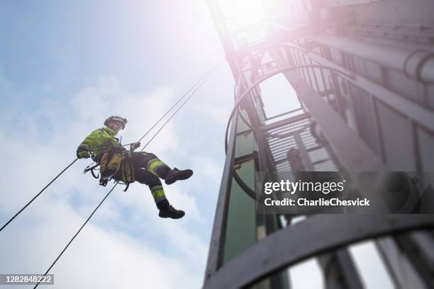 manueller seilzugang techniker - arbeiter abseil vom turm - antenne in sonnenstrahlen - majestätisch stock-fotos und bilder
