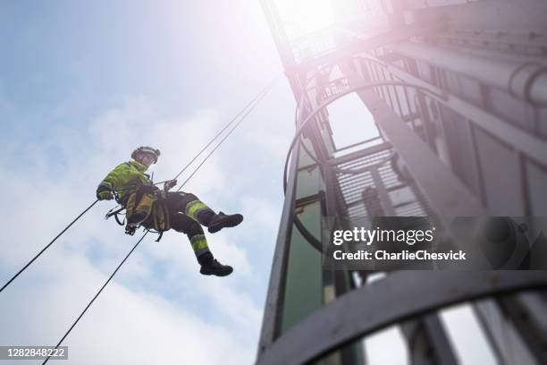 manueller seilzugang techniker - arbeiter abseil vom turm - antenne in sonnenstrahlen - high up stock-fotos und bilder