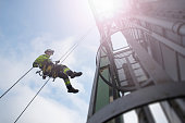 Manual rope access technician - worker abseil from tower - antenna in sun beams