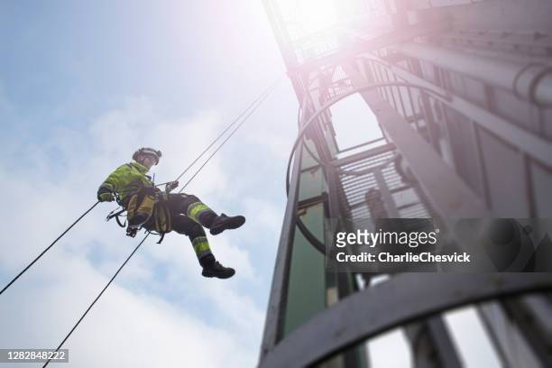 manual rope access technician - worker abseil from tower - antenna in sun beams - safety stock pictures, royalty-free photos & images