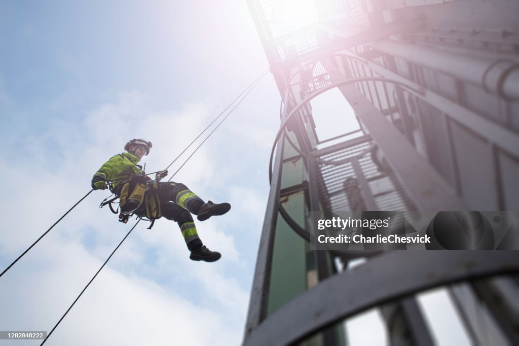 Técnico de acesso manual à corda - abseil trabalhador da torre - antena em raios solares