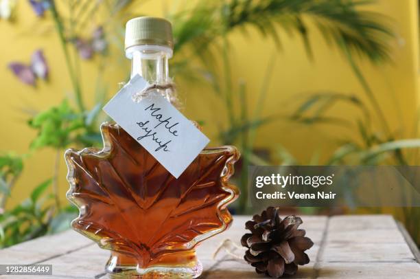 maple syrup in a maple leaf shaped bottle, on a wooden table with handwritten tag/canada - maple syrup stock pictures, royalty-free photos & images
