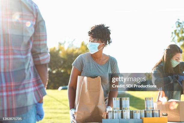 woman with full food bag looks at unseen person - giving tuesday stock pictures, royalty-free photos & images