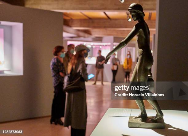Visiting journalists wearing protective masks are seen behind one of the objects on display on the "René Lalique e a Idade do Vidro, Arte e...