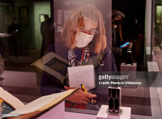Visiting journalist wears a protective mask while watching glass objects on display at the "René Lalique e a Idade do Vidro, Arte e Indústria" during...