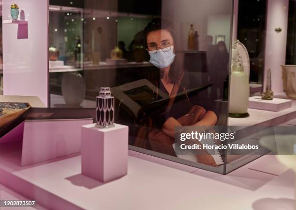 Visiting journalist wears a protective mask while watching glass objects on display at the "René Lalique e a Idade do Vidro, Arte e Indústria" during...