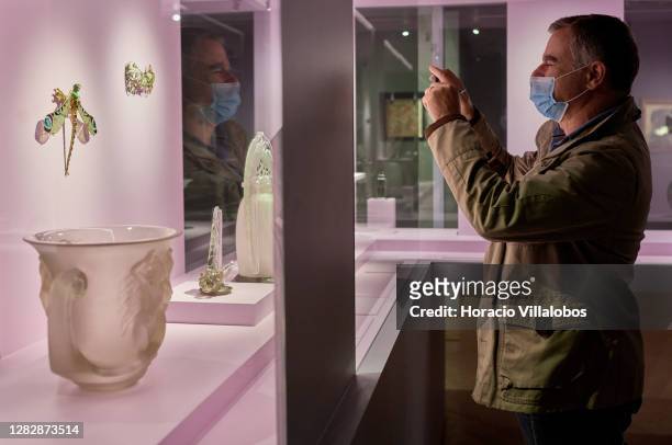 Visiting journalist wears a protective mask while photograping glass objects on display at the "René Lalique e a Idade do Vidro, Arte e Indústria"...