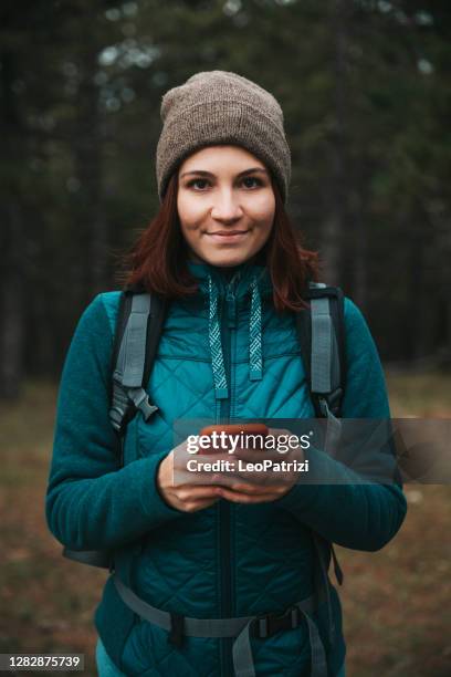 donna che escursioni con uno zaino e tiene in mano un palo da trekking - hiking pole foto e immagini stock