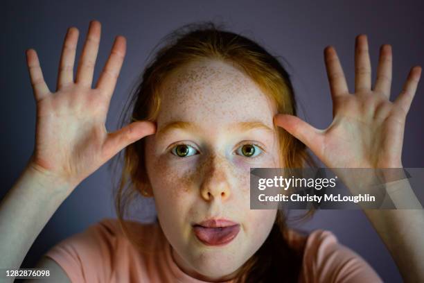 a young girl with long red hair in close-up, sticking tongue out at camera - freckle arm stock pictures, royalty-free photos & images