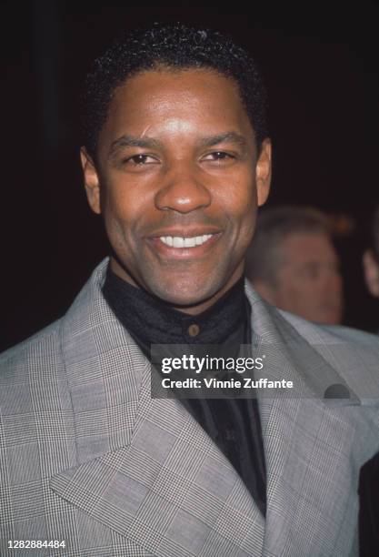 American actor Denzel Washington, wearing a black collarless shirt beneath a grey jacket, attends the premiere of 'The Hurricane' held at the Mann...