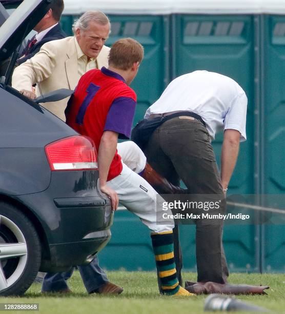 Prince Harry talks with Prince Charles, Prince of Wales' polo manager Robert ffrench Blake as he sits in the boot of his Audi car whilst his police...