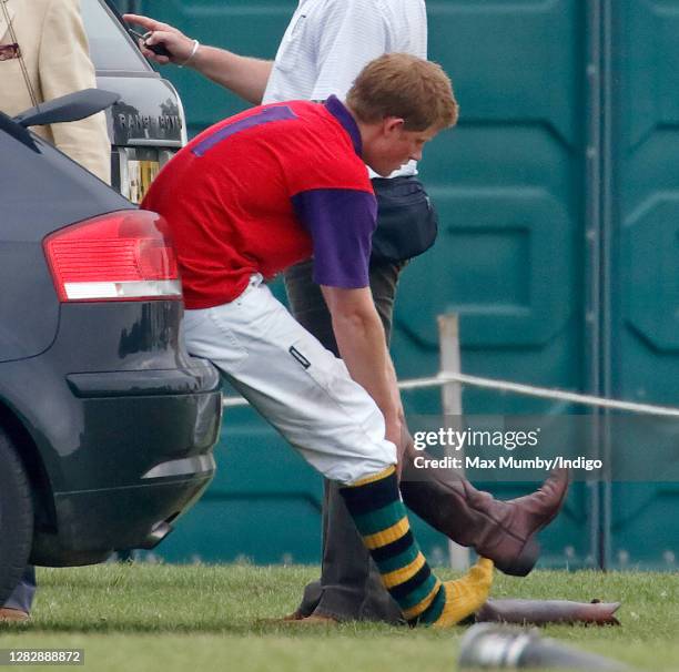 Prince Harry sits in the boot of his Audi car to remove his polo boots after playing in a charity polo match the Beaufort Polo Club on June 18, 2006...