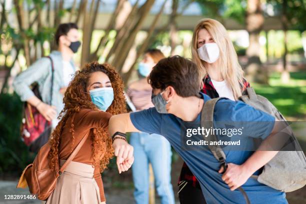 group of young students meeting at the university and doing the new elbow greeting - campus safety stock pictures, royalty-free photos & images