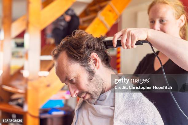 a woman cutting her husband's hair at home - resourceful bildbanksfoton och bilder