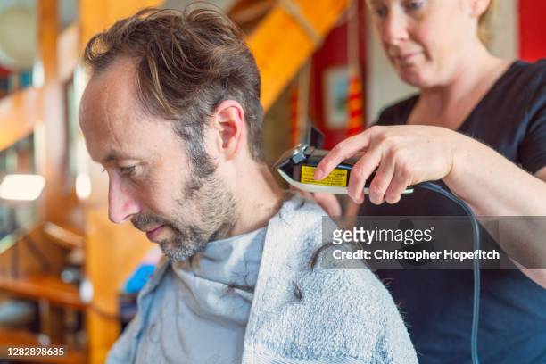 a woman cutting her husband's hair at home during lockdown - christopher guy stock pictures, royalty-free photos & images