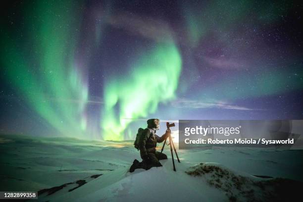 photographer in the snow admiring the northern lights, nordkapp, finnmark - photographer stock-fotos und bilder