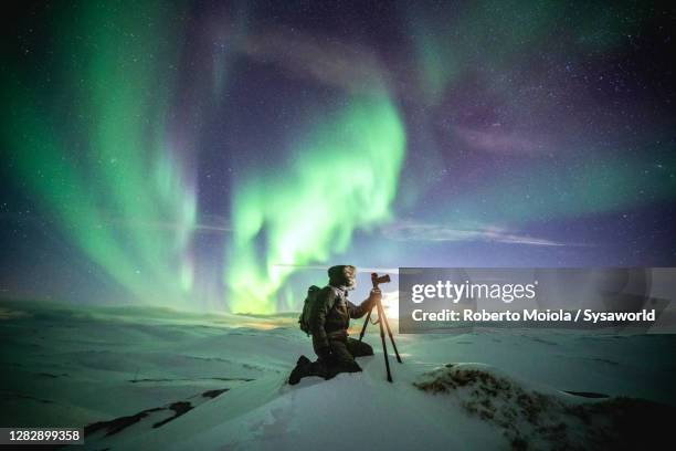 photographer in the snow admiring the northern lights, nordkapp, finnmark - fotografar fotografías e imágenes de stock