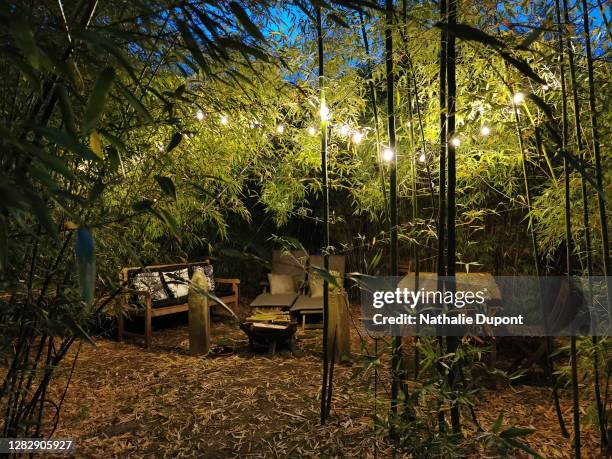 outdoor garden lounge under bamboo at night with a light garland - brasero photos et images de collection