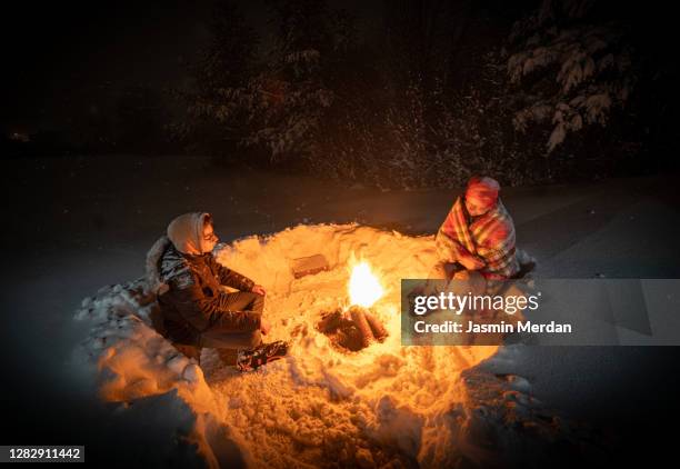 together around camping fireplace in snowy mountain forest at night - hot latin nights stock pictures, royalty-free photos & images