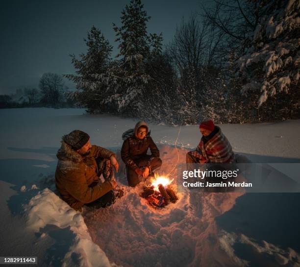together around camping fireplace in snowy mountain forest at night - boy scout camp 個照片及圖片檔