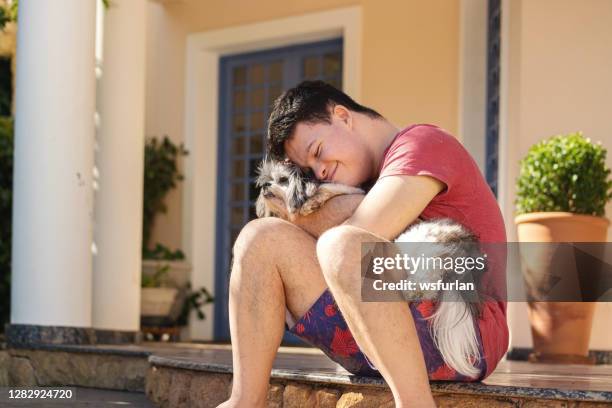 boy with down syndrome playing with his dog. - i love teen boys stock pictures, royalty-free photos & images