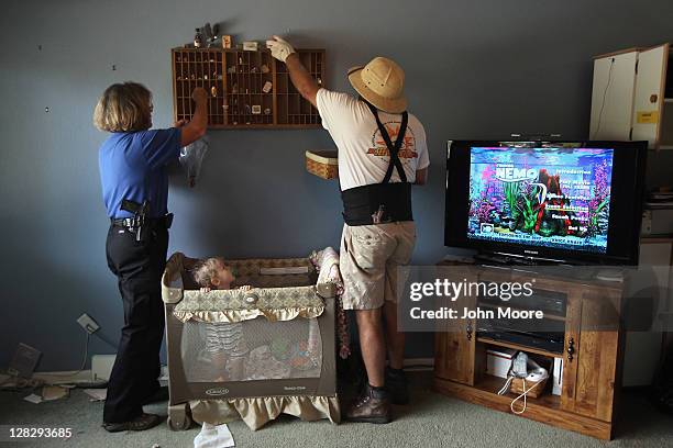 Chase Milam watches as an eviction team and sheriff's seputy remove household goods during a home foreclosure eviction on October 5, 2011 in...