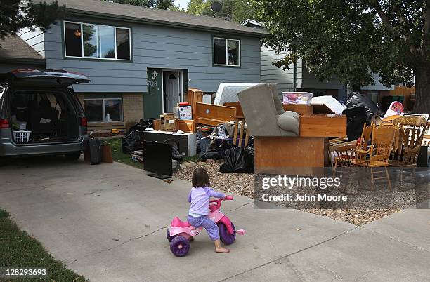 Caitlin Barbiere, 2 1/2, plays in the driveway as her family's possessions sit piled in the front yard during a home foreclosure eviction on October...