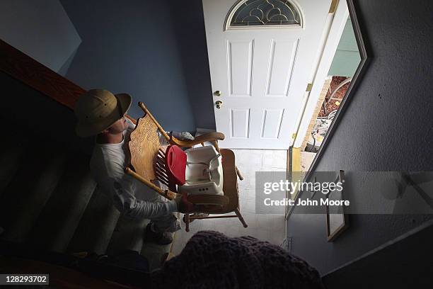 Eviction team leader Steve Fisser removes a child's booster seat and rocking chair during a home foreclosure eviction on October 5, 2011 in Milliken,...