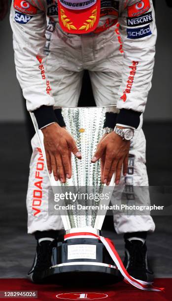 British McLaren Formula One driver Lewis Hamilton on the winners podium affectionately touches the winner's trophy after winning the 2008 Monaco...