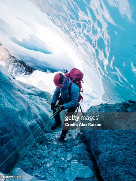 mountain climber spelunker rappels inside a ice cave under glacier - potholing stock pictures, royalty-free photos & images