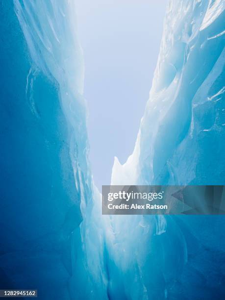 looking up at the blue sky from deep with in a glaciers jagged crevasse - crevasse fotografías e imágenes de stock