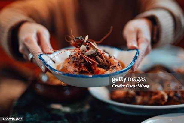 young woman sharing food with friends at restaurant - pescado y mariscos fotografías e imágenes de stock