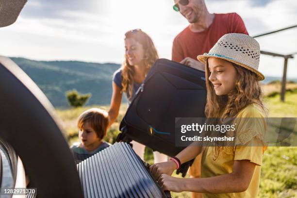 glückliche familie packt ihr gepäck in einen kofferraum. - packen stock-fotos und bilder