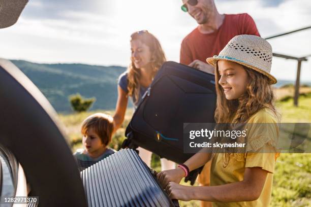gelukkige familie die hun bagage in een autoboomstam inpakt. - suitcase stockfoto's en -beelden