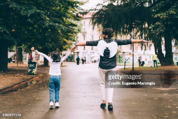 father wearing angel wings, walking with daughter - touched by an angel stockfoto's en -beelden