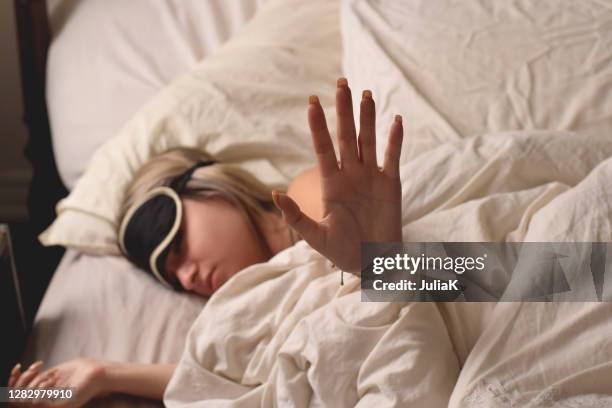 teenage girl wearing an eye mask in bed wanting to be left alone - hangover stockfoto's en -beelden