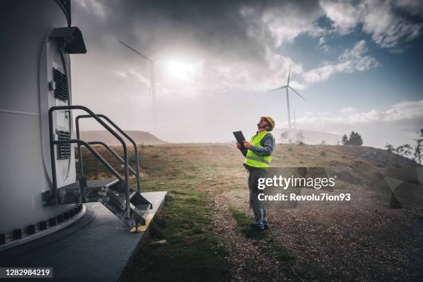 junger ingenieur beim schauen und prüfen von windkraftanlagen - elektrischer generator stock-fotos und bilder