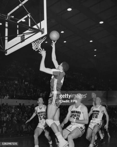 Seattle Redhawks basketball team player attempts a shot as the players of the opposite team, Oregon State Beavers, look at the basket, US, circa 1960.