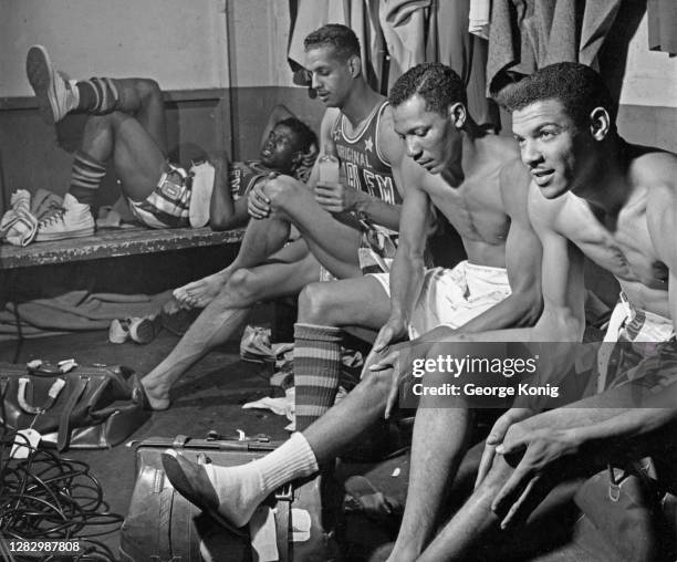Harlem Globetrotters players rub lotions on ligaments ahead of a basketball game in a locker room, US, May 1951. Second from left is Rookie Brown.