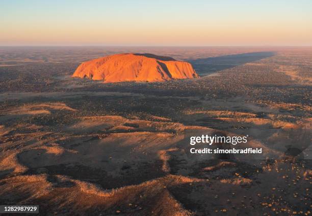 aerial view of uluru in the evening sun - uluru stock pictures, royalty-free photos & images