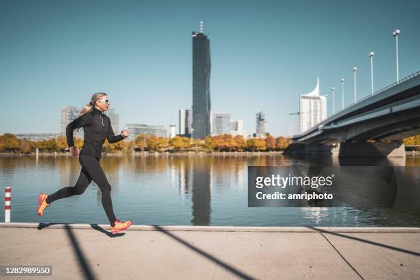 vrouw die langs stedelijke waterkant van stad aan het joggen is - james last awarded badge of honour by city of vienna stockfoto's en -beelden