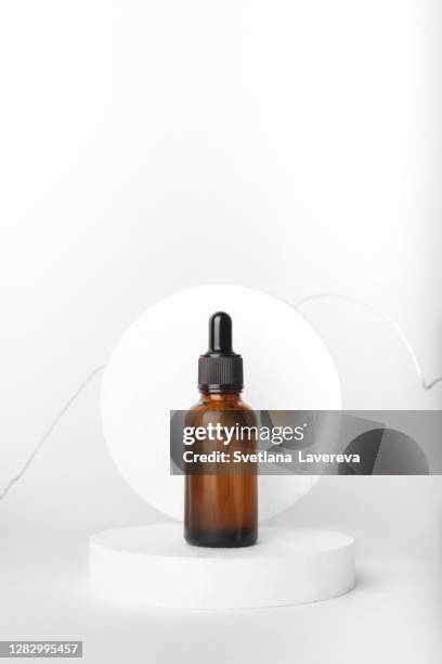 a glass bottle stands with aromatic oil on a circle. - serum sample stock pictures, royalty-free photos & images