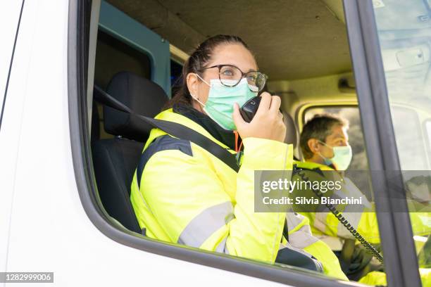paramedic in ambulance talking on radio - paramedic stock pictures, royalty-free photos & images