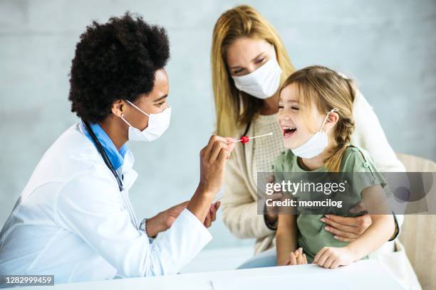 mujer doctora tomando la prueba de hisopo de garganta / pcr de niña pequeña - instrumento de la reacción en cadena de la polimerasa fotografías e imágenes de stock