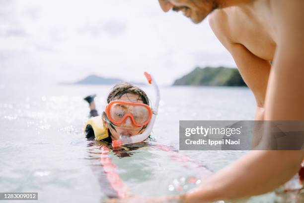 father teaching daughter how to snorkel, okinawa, japan - schnorchel stock-fotos und bilder