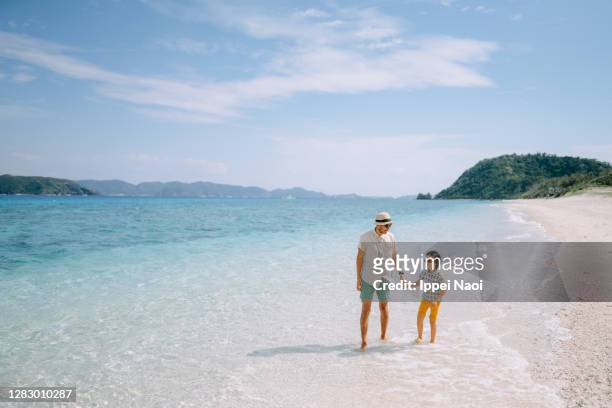 father and child walking together on tropical beach - beach holiday stock-fotos und bilder